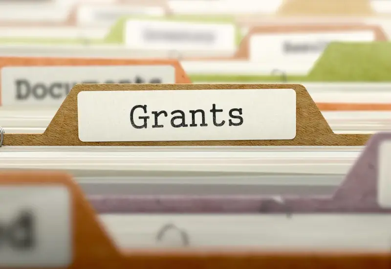 A close up a file cabinate and a folder title 'Grants'