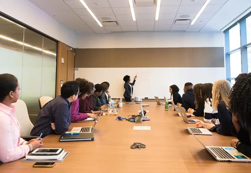 A group of people in a board room watching a presentation