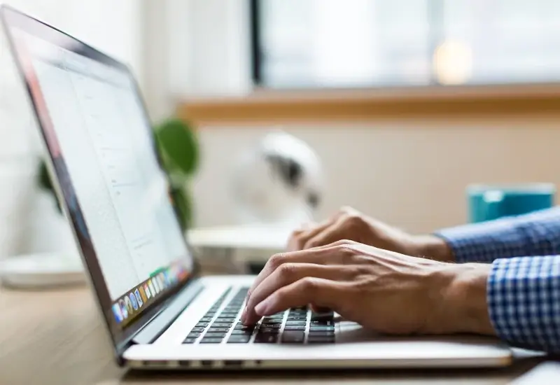 Hands typing on a laptop