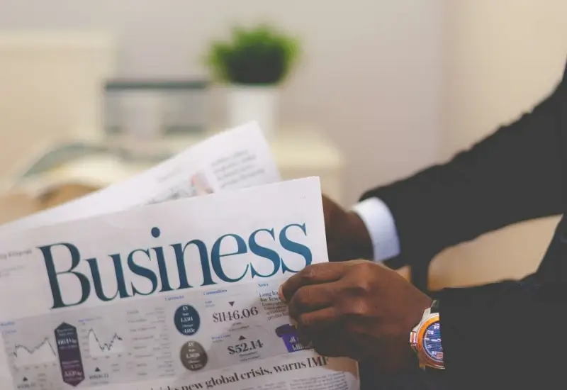 A person holding a magazine with the title Business